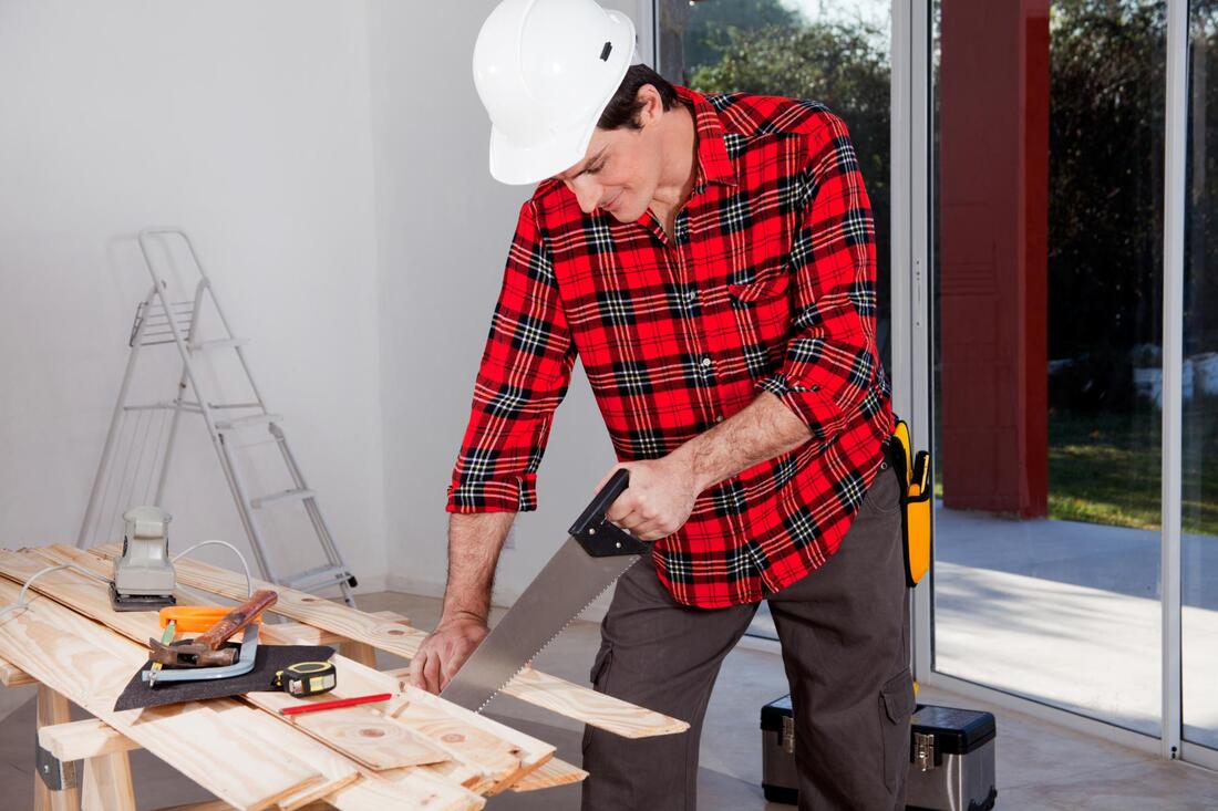man wearing a safety hat is sawing a piece of wood
